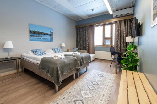 a bedroom with two beds with blue walls and a television at Hotelli Viikinhovi in Keuruu