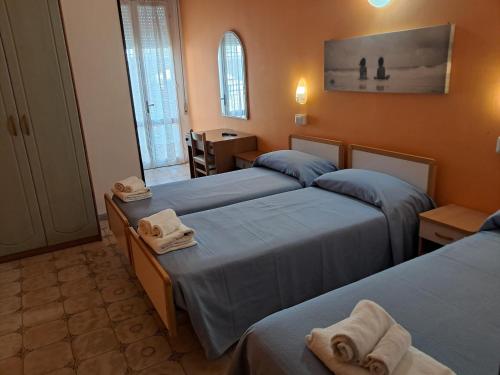 a room with three beds with towels on them at Hotel Adriatico in Bellaria-Igea Marina