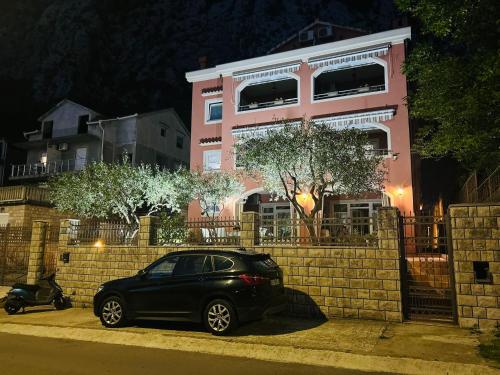 a black car parked in front of a pink building at Radonjić Apartments in Kotor