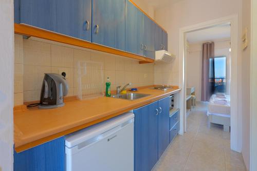 a kitchen with blue cabinets and a sink at Sueño beach hotel in Polychrono