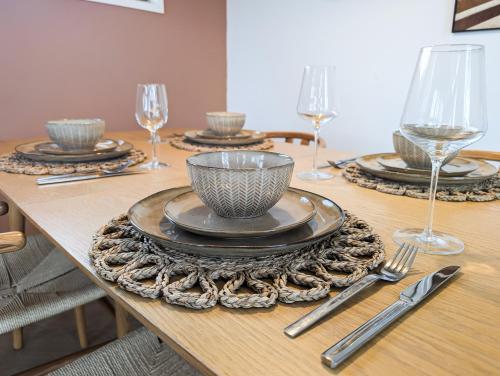 a wooden table with plates and wine glasses on it at Wellness Chalet Hellendoorn met Hot tub en Sauna in Haarle