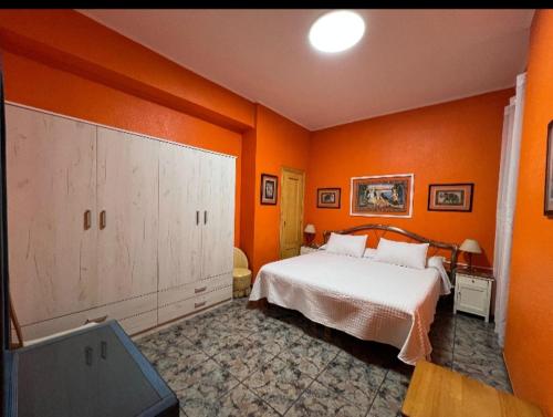 a bedroom with orange walls and a white bed in it at Broadway es Mar in El Perelló