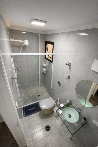 a bathroom with a shower and a toilet and a sink at Apto pe na areia 3 dorm ar cond in Caraguatatuba