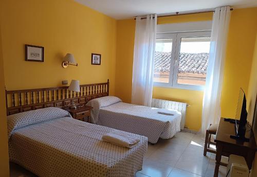 a hotel room with two beds and a window at Hostal Restaurante Yagual in Sahagún