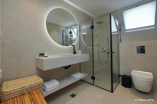 a bathroom with a shower and a sink and a toilet at Shilo Boutiqe Suites in Mishmār Hāyardin
