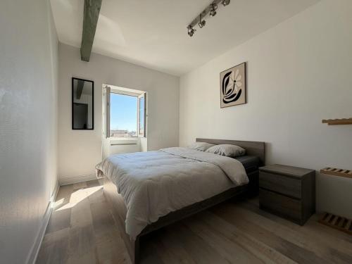 a white bedroom with a bed and a window at Appartement VAIS in Cognac