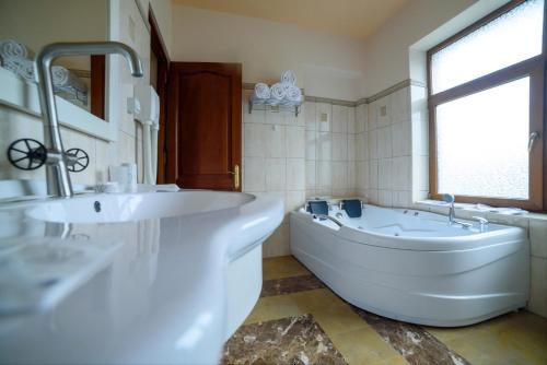 a white bathroom with a tub and a sink at Virginia Gardens in Băile Govora