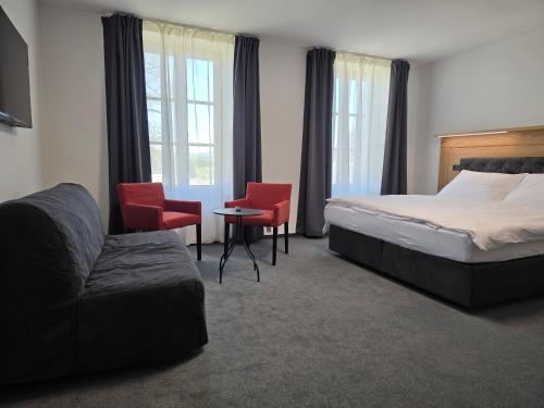 a hotel room with a bed and chairs and a couch at hostINNec in Dolní Dvořiště