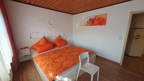 a bedroom with a bed with orange pillows and a chair at Haus Waldesruh, 3 Ferienwohnungen in Hemfurth-Edersee