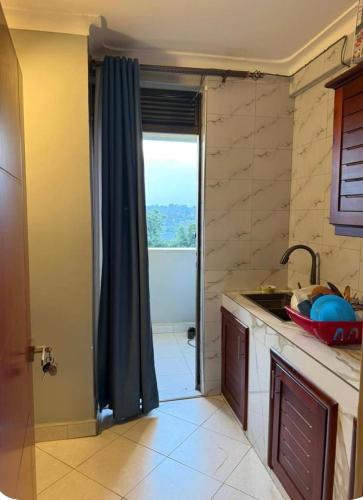 a kitchen with a sink and a shower with a window at Backpackersnest in Entebbe