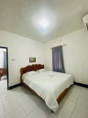 a bedroom with a large bed with white sheets at Tiba Meka Homestay in Komodo Labuan Bajo Airport