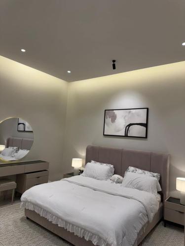 a bedroom with a large white bed and a mirror at منتجع دار DAR Resort in Hail