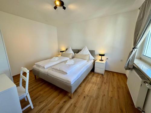 a bedroom with a white bed and a chair and a window at Apartment SeeZeit - Top Lage & nahe am Bodensee in Friedrichshafen
