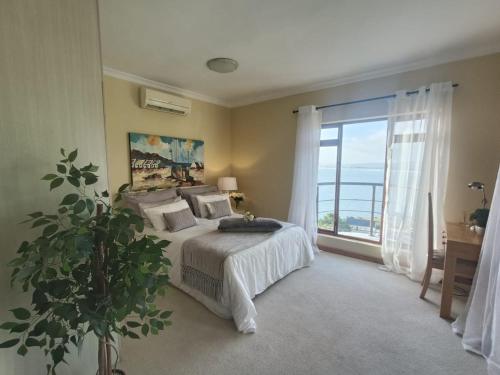 a bedroom with a bed and a large window at Villa Solace in Gordonʼs Bay