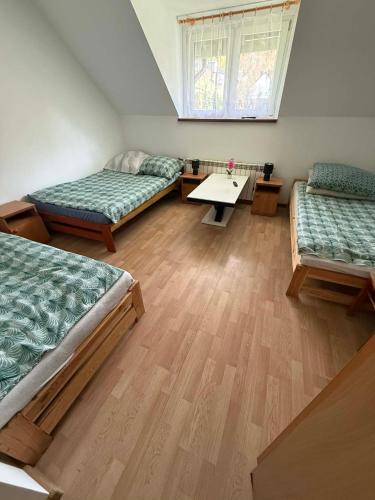 a room with three beds and a table in it at agroturystyka Pensjonat PAULA in Muszyna