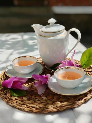 a tea set on a basket with two cups and flowers at Bistrički mir - Rustic House in Petrovac na Mlavi