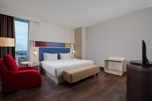 a hotel room with a bed and a red chair at Amandaru Hotel Pekalongan in Pekalongan