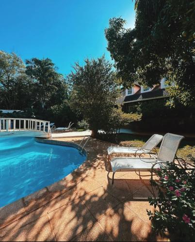 a swimming pool with two lounge chairs next to it at Hotel Posada La Sorgente in Puerto Iguazú