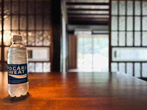 a bottle of water sitting on a wooden table at 古民家宿 Mutsu Traditional Japanese House Inn MUTSU in Ōtaki