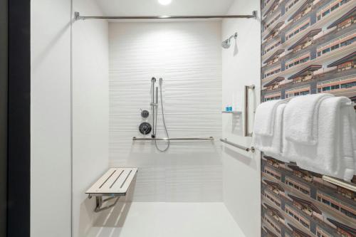 a white bathroom with a bench and a shower at Aloft by Marriott Denver North Westminster in Westminster