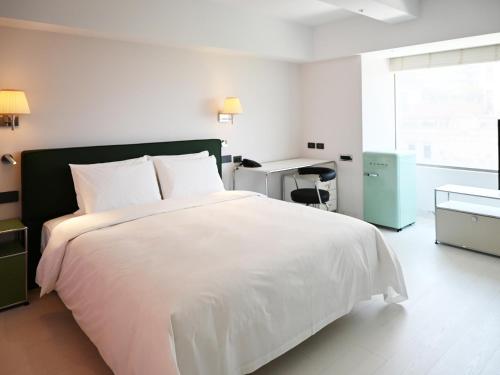 a bedroom with a large white bed and a desk at OOD Hotel Taipei DunhuaNorth in Taipei