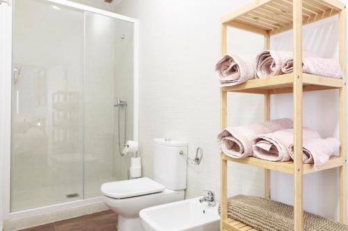 a bathroom with a white toilet and a shelf with towels at Duplex con vistas en el centro de Aracena in Aracena