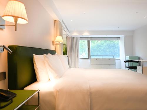 a bedroom with a large white bed with a window at OOD Hotel Taipei DunhuaNorth in Taipei