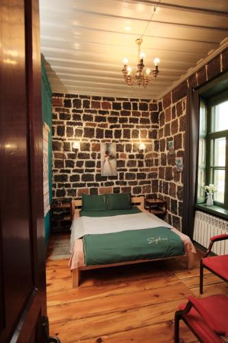 a bedroom with a bed and a brick wall at Onoyi Tun Guest House in Gyumri