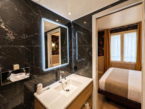 a bathroom with a sink and a bed at Hôtel de Notre-Dame in Paris