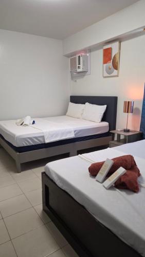 two beds in a hotel room with towels on them at Plumera Mactan Condo unit in Bankal