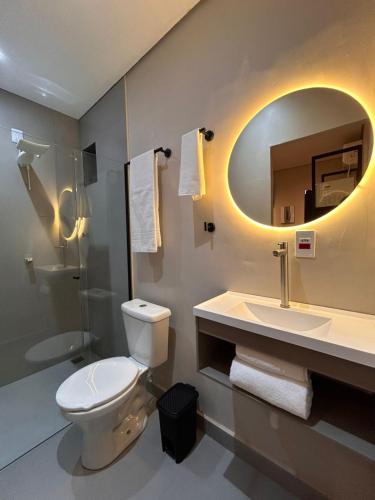 a bathroom with a toilet and a sink and a mirror at Studio Moderno e Prático Wi-Fi Rápido e AC in Ribeirão Preto