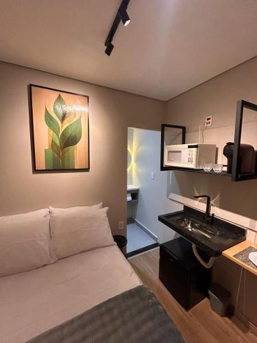 a bedroom with a bed and a desk with a sink at Studio Moderno e Prático Wi-Fi Rápido e AC in Ribeirão Preto