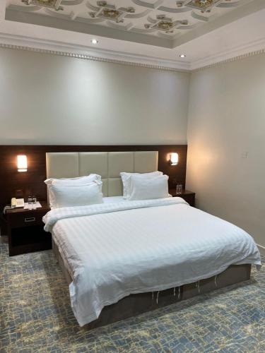 ein Schlafzimmer mit einem großen Bett mit weißen Laken und Kissen in der Unterkunft Hotel Berg Rappeg in Rabigh