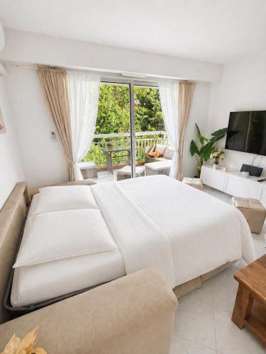 a bedroom with a large white bed and a living room at Le Saint Michel - MENTON#MONACO - 6 PERSONS - Parking- bord de mer in Menton