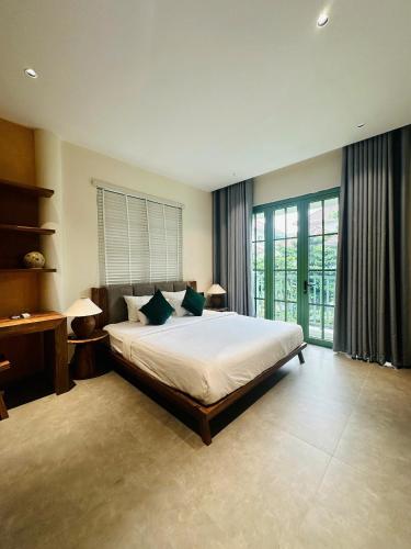a bedroom with a large bed and a desk and window at PhuQuoc Homestay in Long Bình
