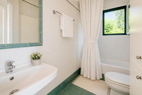 a white bathroom with a sink and a toilet at Golden Tiara Apartment in Barbati