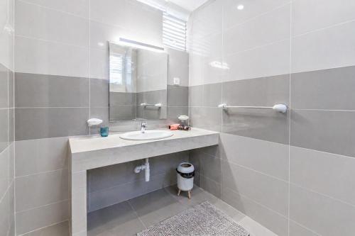 a white bathroom with a sink and a mirror at Anarma Oceanfront Apartment in Wattala