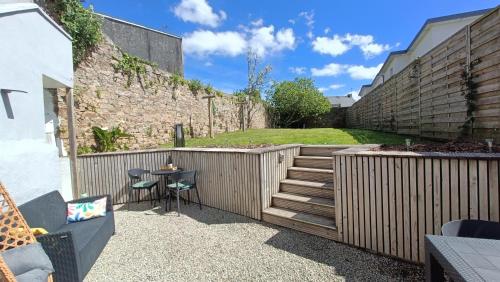 a patio with a wooden fence and a table and chairs at Gîte KERBOURC'H charmant et confortable, mer et plages à 3km, Ploudalmézeau in Ploudalmézeau