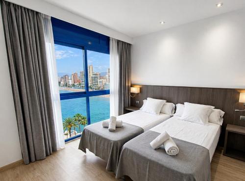 a hotel room with two beds and a large window at Hotel Bossh Lido in Benidorm