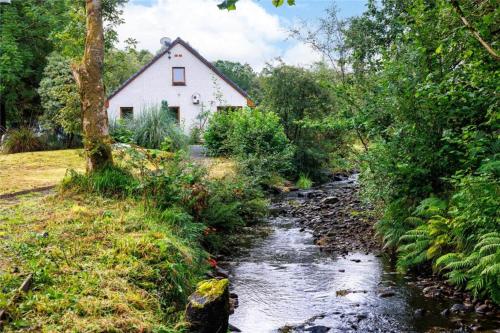 a house on a hill next to a stream at Bluebell Cottage in Tarbert