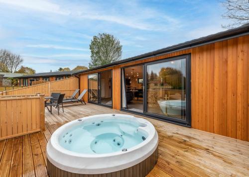 a hot tub on the deck of a house at Ashlea Pools Lodges in Hoptonheath