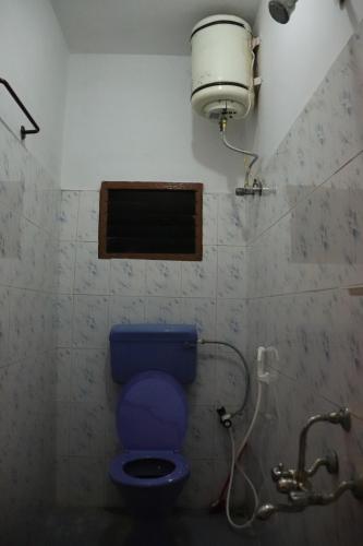 a bathroom with a blue toilet in a room at Pinetree Stay in Kodaikānāl