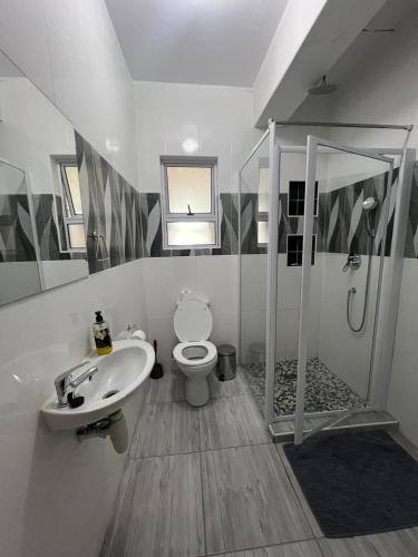 a bathroom with a shower and a toilet and a sink at 112 On Park Drive in Gqeberha