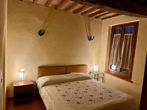 a bedroom with a bed and two lamps on tables at Nido in Toscana - Appartamento in Centro Storico con Aria Condizionata in Buonconvento