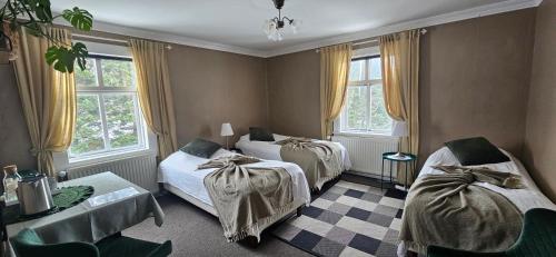 a bedroom with two beds and two windows at Árból Guesthouse in Húsavík