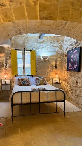 a bedroom with a bed in a stone wall at L'Artiste Guest House in Xagħra