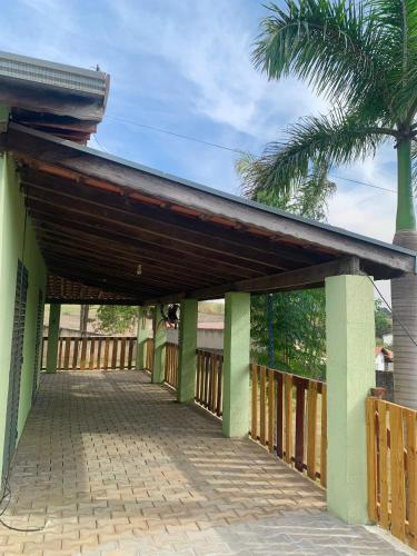 a wooden covered walkway to a house with a palm tree at Chácara do Neno in Limeira