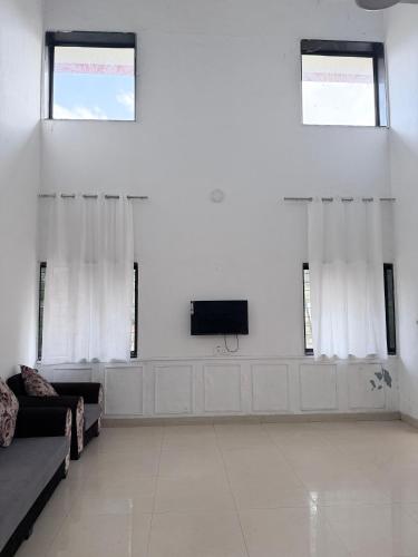 a living room with a couch and a tv at Hidden Hearts Cottage in Lonavala