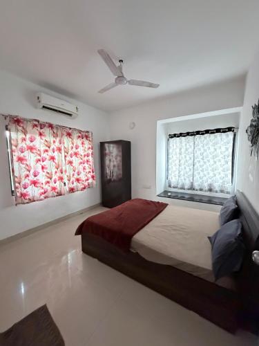 a bedroom with a large bed and two windows at Hidden Hearts Cottage in Lonavala