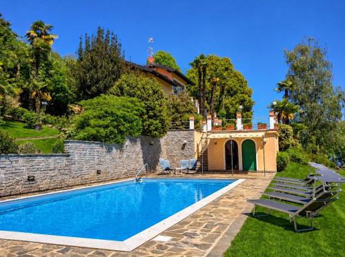 a swimming pool in a yard next to a stone wall at Villa Romilda in Arona